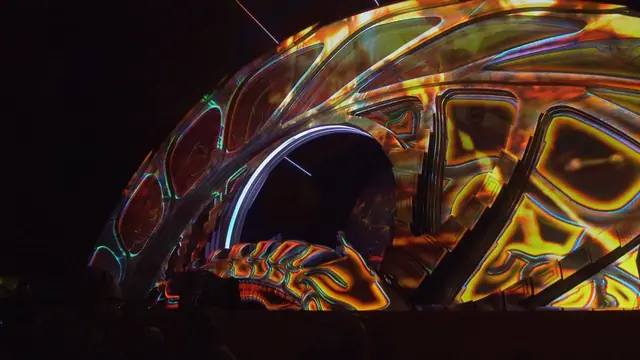 Palco Alchemy no Boom Festival 2023 com video mapping colorido sobre estrutura orgânica
