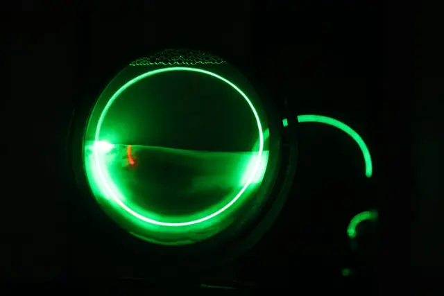 SiO2: anel de laser verde a atravessar areia dentro de vidro