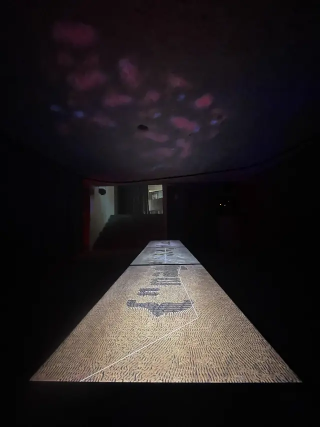Instalação SOLO em Braga: mesa longa iluminada por projeção de dados sísmicos