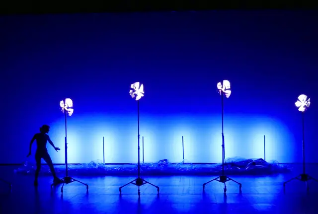 Una Isla, Agrupación Señor Serrano: performer em palco azul com ventoinhas iluminadas